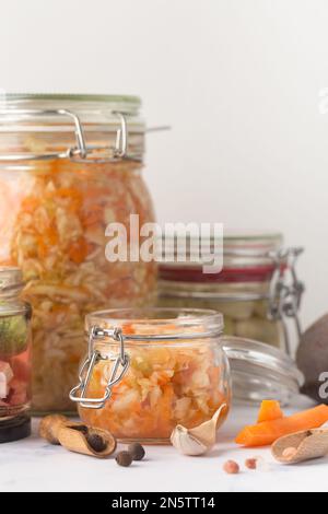 Pots en verre avec divers légumes marinés et ingrédients sur fond de marbre Banque D'Images