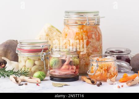 Pots en verre avec divers légumes marinés et ingrédients sur fond de marbre Banque D'Images
