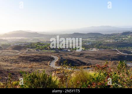 Vue depuis le dessus d'une terre rurale vallonnée parsemée de ranchs et de fermes en Californie au coucher du soleil en automne Banque D'Images