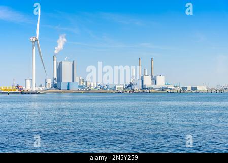 Centrales électriques au charbon avec des cheminées élevées dans un port. L'éolienne ATall est en premier plan. Banque D'Images