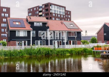 Les maisons de front de mer écoénergétiques avec panneaux solaires sur le toit au coucher du soleil Banque D'Images