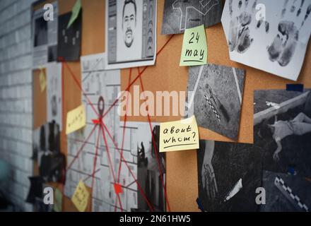 Tableau de détection avec autocollants, photos de scènes de crime et fils rouges, gros plan Banque D'Images