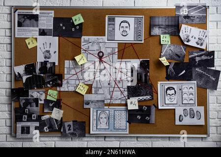Tableau de détection avec empreintes digitales, photos, carte et indices reliés par une ficelle rouge sur un mur de briques blanches Banque D'Images