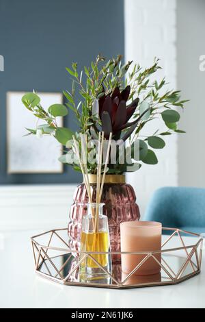 Magnifique bouquet de branches d'eucalyptus, bougie et diffuseur de parfum de roseau aromatique sur table blanche à l'intérieur. Éléments intérieurs Banque D'Images