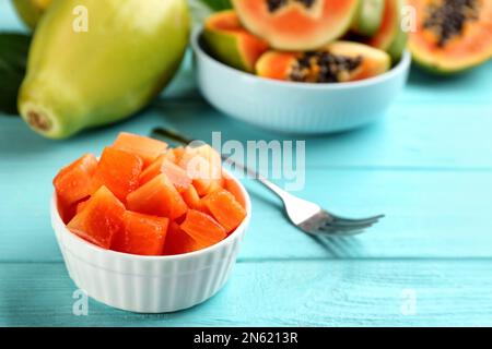 Dés de papaye mûre fraîche dans un bol sur une table en bois turquoise Banque D'Images