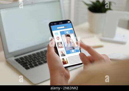 Jeune femme visitant le site de rencontres en ligne via smartphone à l'intérieur, gros plan Banque D'Images