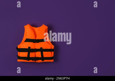 Gilet de sauvetage orange sur fond violet. Espace pour le texte Banque D'Images