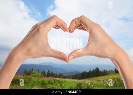 Femme faisant le coeur avec les mains à l'extérieur le jour ensoleillé, gros plan Banque D'Images