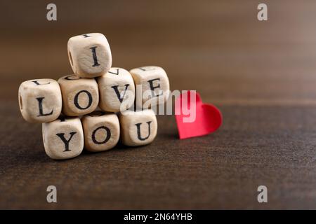 Cubes avec des mots Je vous aime et coeur de papier sur table en bois Banque D'Images