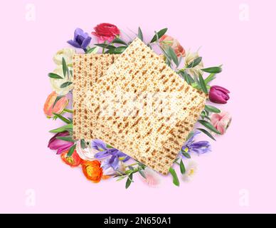 Savoureux matzos et fleurs sur fond rose, plat. Fête de la Pâque (Pesach) Banque D'Images