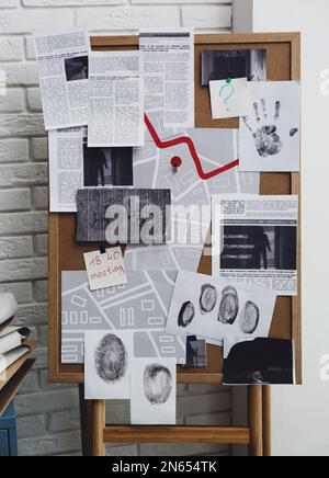 Tableau de détection avec empreintes digitales, photos de scènes de crime et carte près du mur de briques blanches à l'intérieur Banque D'Images
