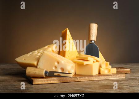 Différentes sortes de fromage, fourchette et couteau sur table en bois Banque D'Images