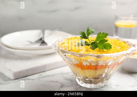 Salade russe traditionnelle Mimosa servie sur une table en marbre blanc. Espace pour le texte Banque D'Images