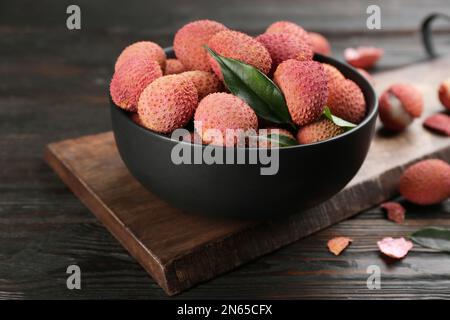 Fruits de lychee mûrs frais dans un bol sur une table en bois sombre Banque D'Images