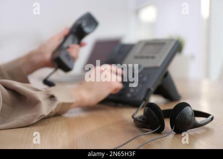 Femme utilisant un téléphone de bureau au bureau, concentrez-vous sur le micro-casque. Service d'assistance téléphonique Banque D'Images