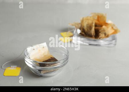 Bol en verre avec sac de thé usagé sur table grise Banque D'Images