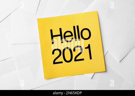 Note avec texte Hello 2021 sur feuilles de papier, vue de dessus Banque D'Images