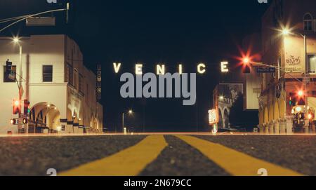 Venice Beach Sign illumine la rue lors d'une soirée tranquille avec personne sur la route. Banque D'Images