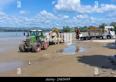 Tauranga Nouvelle-Zélande - 8 février 2023: Digger sur remorque derrière tracteur sur la plage. Banque D'Images