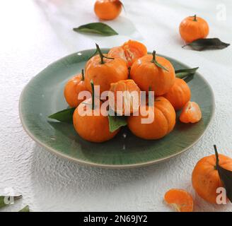 pile de tangerines sur une assiette verte Banque D'Images