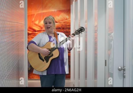 Hambourg, Allemagne. 09th févr. 2023. Stefanie Ansul-Weissner, une femme de ménage de STR Stadtteilreinigungsgesellschaft mbH, joue sa guitare et chante une chanson dans les toilettes publiques de Am Niederhafen. À Hambourg, sur la promenade de l'Elbe, il y a un petit endroit tranquille qui n'est pas du tout si calme, grâce à un gardien de toilettes musicales, et qui est également de bonne humeur. (À dpa: 'Bonne humeur en faisant wee-wee - la femme de toilette de Hambourg joue de la guitare') Credit: Marcus Brandt/dpa/Alamy Live News Banque D'Images