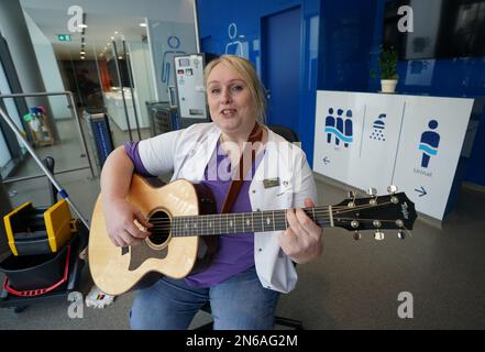 Hambourg, Allemagne. 09th févr. 2023. Stefanie Ansul-Weissner, une femme de ménage de STR Stadtteilreinigungsgesellschaft mbH, joue sa guitare et chante une chanson dans les toilettes publiques de Am Niederhafen. À Hambourg, sur la promenade de l'Elbe, il y a un petit endroit tranquille qui n'est pas du tout si calme, grâce à un gardien de toilettes musicales, et qui est également de bonne humeur. (À dpa: 'Bonne humeur en faisant wee-wee - la femme de toilette de Hambourg joue de la guitare') Credit: Marcus Brandt/dpa/Alamy Live News Banque D'Images