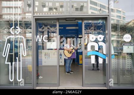 Hambourg, Allemagne. 09th févr. 2023. Stefanie Ansul-Weissner, une femme de ménage de STR Stadtteilreinigungsgesellschaft mbH, joue sa guitare et chante une chanson dans les toilettes publiques de Am Niederhafen. À Hambourg, sur la promenade de l'Elbe, il y a un petit endroit tranquille qui n'est pas du tout si calme, grâce à un gardien de toilettes musicales, et qui est également de bonne humeur. (À dpa: 'Bonne humeur en faisant wee-wee - la femme de toilette de Hambourg joue de la guitare') Credit: Marcus Brandt/dpa/Alamy Live News Banque D'Images