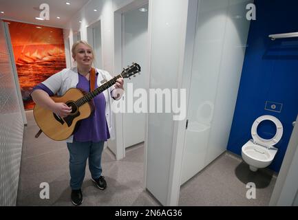 Hambourg, Allemagne. 09th févr. 2023. Stefanie Ansul-Weissner, une femme de ménage de STR Stadtteilreinigungsgesellschaft mbH, joue sa guitare et chante une chanson dans les toilettes publiques de Am Niederhafen. À Hambourg, sur la promenade de l'Elbe, il y a un petit endroit tranquille qui n'est pas du tout si calme, grâce à un gardien de toilettes musicales, et qui est également de bonne humeur. (À dpa: 'Bonne humeur en faisant wee-wee - la femme de toilette de Hambourg joue de la guitare') Credit: Marcus Brandt/dpa/Alamy Live News Banque D'Images