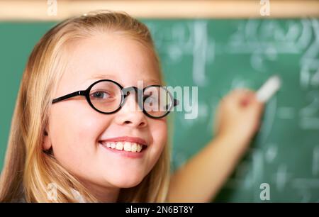 Montrer à ses camarades de classe comment ça s'est fait. Portrait d'une jolie fille blonde en utilisant de la craie en classe. Banque D'Images