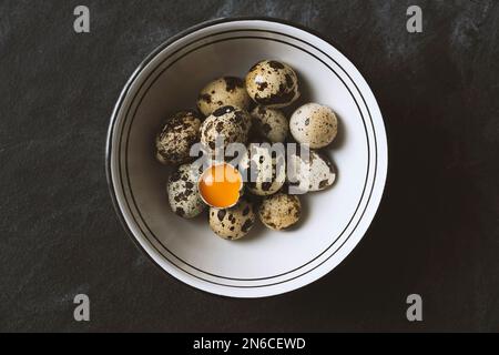 Œufs de caille frais bio gratuits dans un bol en céramique sur fond rustique noir. Vue de dessus. Banque D'Images