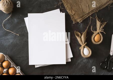 Préparatifs de Pâques. Photo de table avec des magazines blancs à couverture vierge et des œufs de lapin de pâques. Banque D'Images