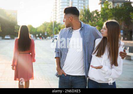 Homme disloyal regardant une autre femme en marchant avec sa petite amie à l'extérieur Banque D'Images