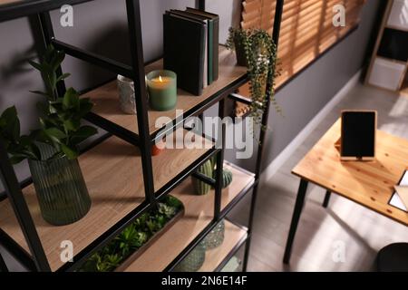 Étagères avec décor différent, livres et plantes de maison près du mur gris dans la chambre. Design intérieur Banque D'Images