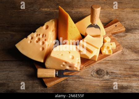 Différentes sortes de fromage, fourchette et couteau sur table en bois Banque D'Images