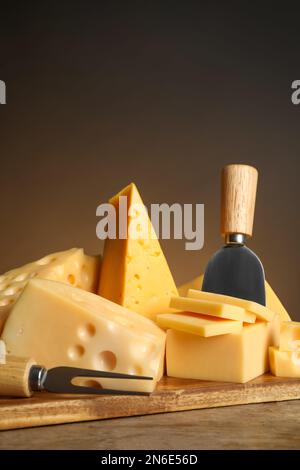 Différentes sortes de fromage, fourchette et couteau sur table en bois Banque D'Images