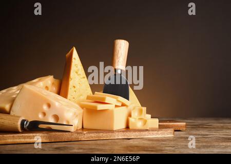 Différentes sortes de fromage, fourchette et couteau sur table en bois Banque D'Images