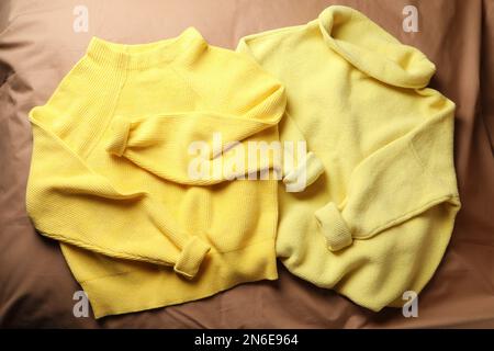 Beaux chandails chauds jaunes sur drap brun, plat Banque D'Images