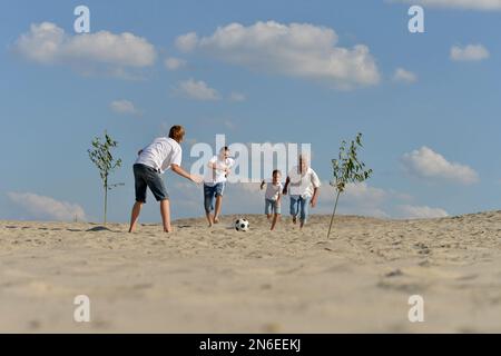 Famille jouant au football sur une plage en été 24 Banque D'Images