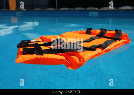 Gilet de sauvetage orange vif flottant dans la piscine Banque D'Images