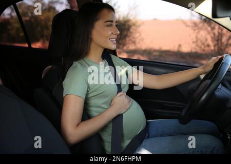 Jeune femme enceinte avec ceinture de sécurité en voiture Banque D'Images