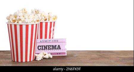 Tasses avec pop-corn délicieux et billets sur table en bois sur fond blanc Banque D'Images