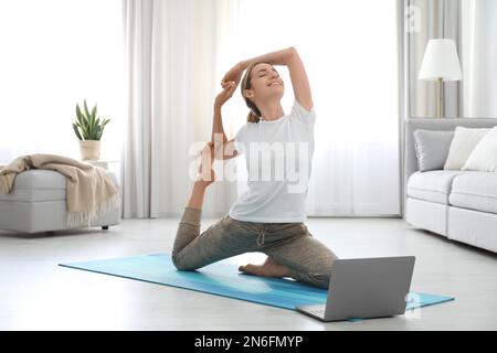 Femme ayant un cours de vidéo en ligne via un ordinateur portable à la maison. Cours de yoga à distance pendant une pandémie de coronavirus Banque D'Images