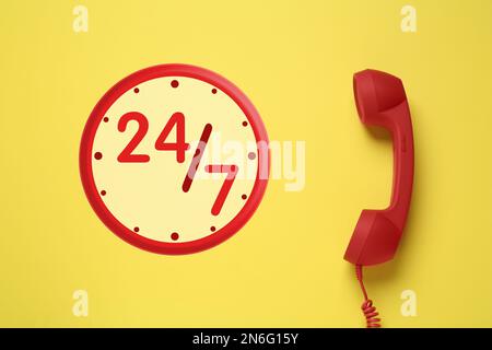 service d'assistance téléphonique 24h/24/7, 7j Combiné rouge sur fond jaune, vue du dessus Banque D'Images