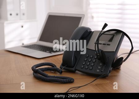 Téléphone fixe et casque sur une table en bois à l'intérieur. Service d'assistance téléphonique Banque D'Images