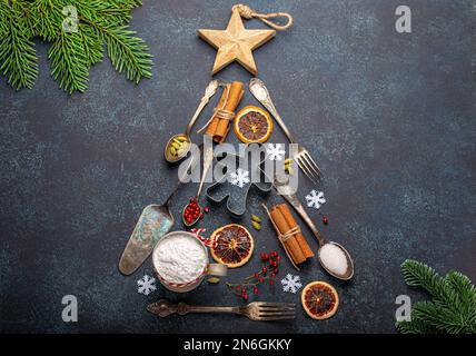 Composition de Noël et du nouvel an faite en forme de sapin de Noël à partir d'outils de cuisine et d'ingrédients de cuisine sur béton de pierre bleu foncé Banque D'Images