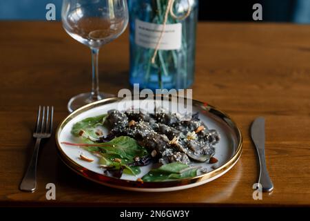 Un morceau de saumon grillé poivre citron et sel sur une assiette brune avec des feuilles de laitue. arrière-plan en bois. Photo de haute qualité Banque D'Images