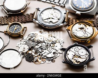 pile de pièces de rechange anciennes et de montres mécaniques sur table en bois dans l'atelier horloger Banque D'Images