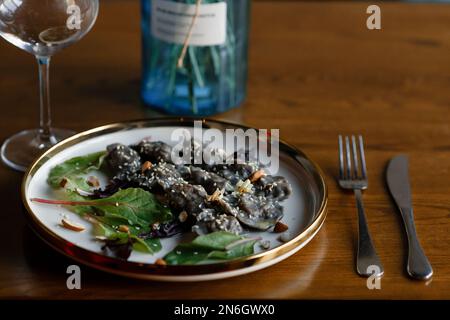 Un morceau de saumon grillé poivre citron et sel sur une assiette brune avec des feuilles de laitue. arrière-plan en bois. Photo de haute qualité Banque D'Images