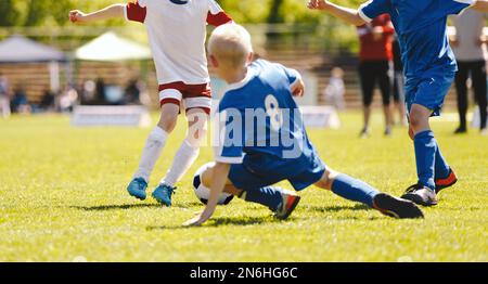 Le football s'attaque au moment présent. Compétence de s'attaquer dans le jeu de football. Les enfants rejouent le ballon de football sur le terrain de pelouse. Footballeurs enfants dans un duel. École de course Banque D'Images