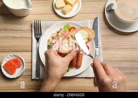 Femme qui a tarté du beurre sur des toasts à la table, vue de dessus. Service de buffet Banque D'Images